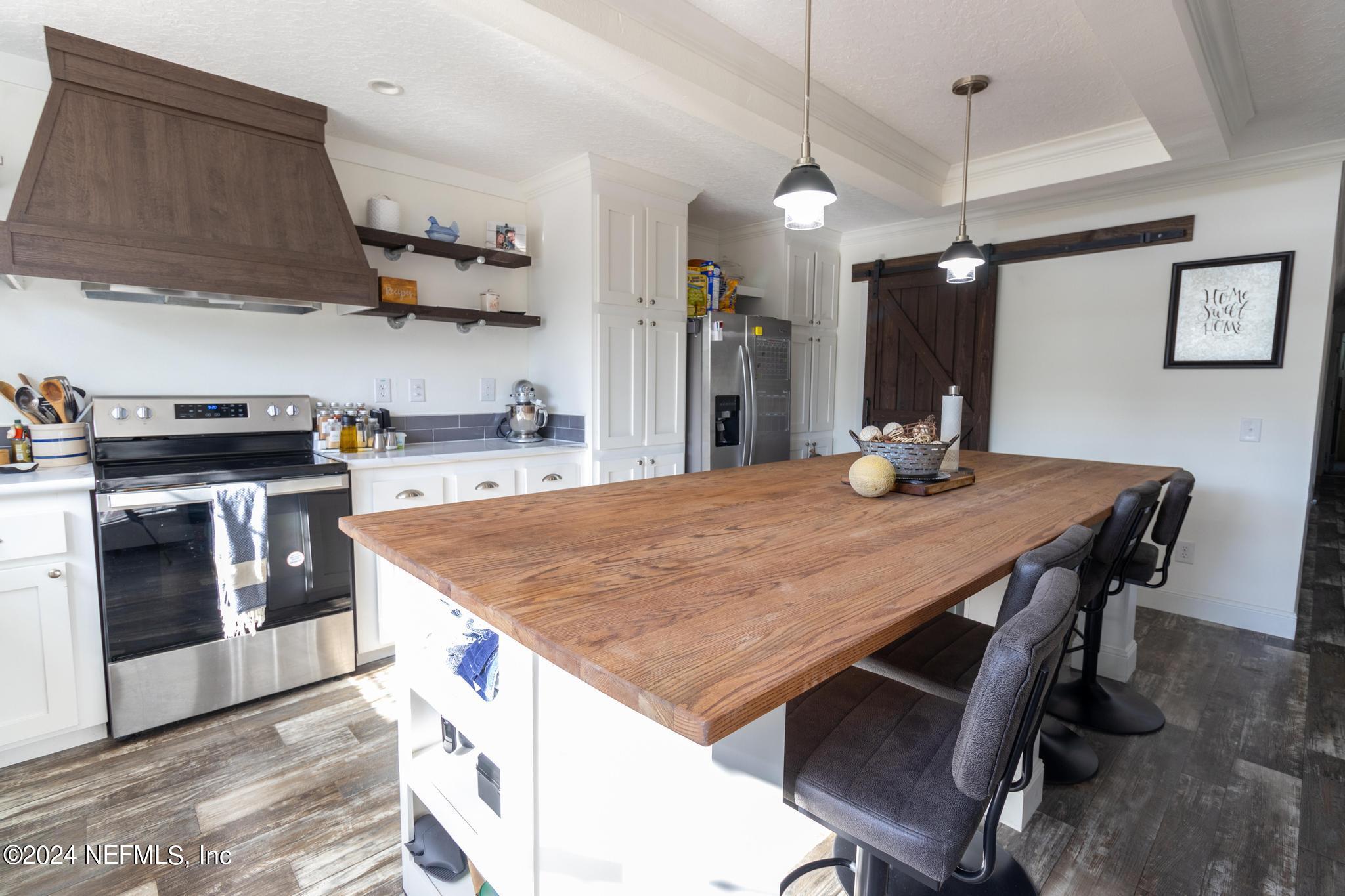 121 Honeysuckle Trail Hawthorne, FL 32640 - Photo 8 of 44 a kitchen with stainless steel appliances granite countertop a stove a refrigerator a sink a dining table and chairs with wooden floor