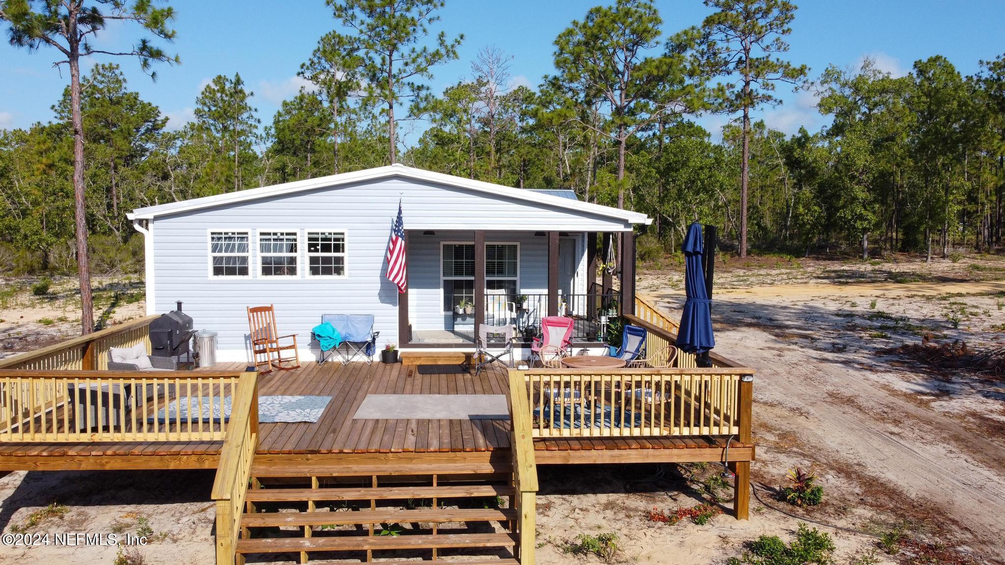 121 Honeysuckle Trail Hawthorne, FL 32640 - Photo 9 of 44 a view of a house with wooden deck and furniture