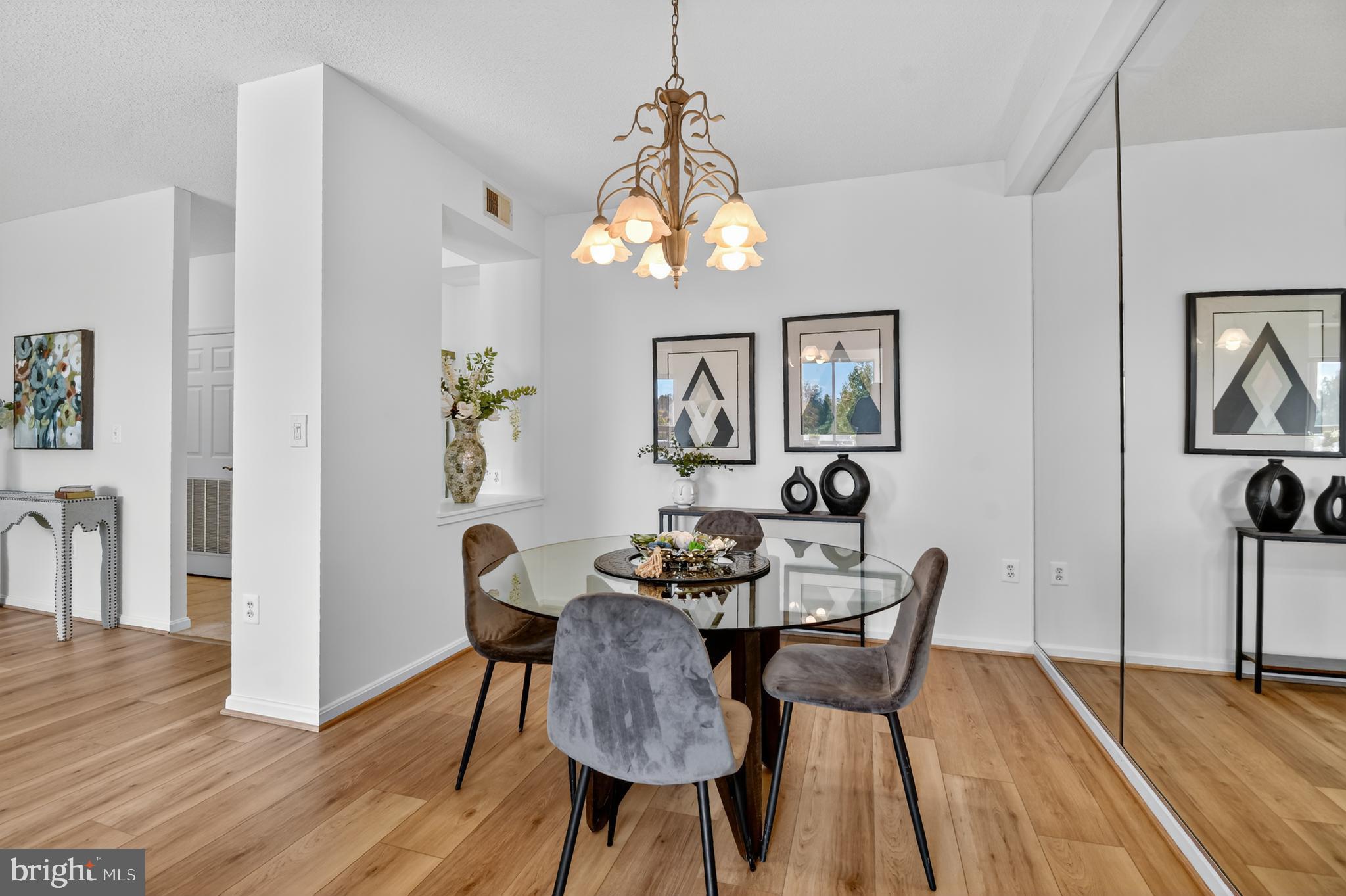 3005 South Leisure World Boulevard, Unit 426 Silver Spring, MD 20906 - Photo 14 of 45 a dining room with wooden floor a chandelier a glass table and chairs