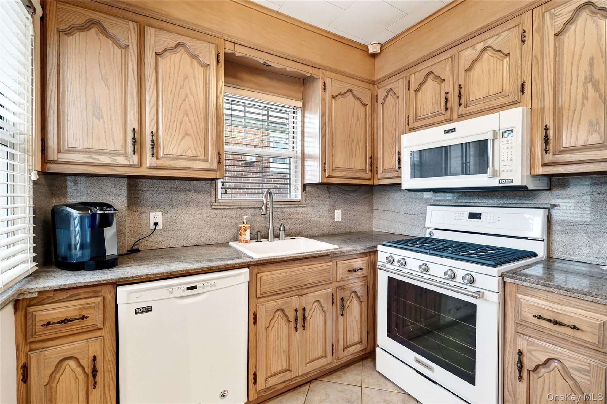 3334 Country Club Road Bronx, NY 10465 - Photo 18 of 49 Kitchen featuring white appliances, tasteful backsplash, light tile patterned floors, and light stone counters
