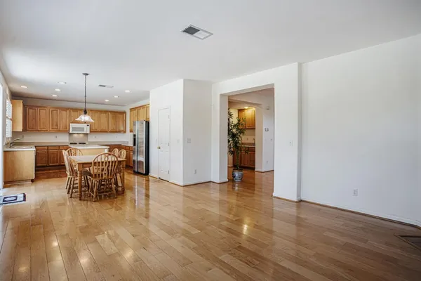 a kitchen with stainless steel appliances granite countertop a stove a refrigerator a kitchen island a dining table and chairs with wooden floor