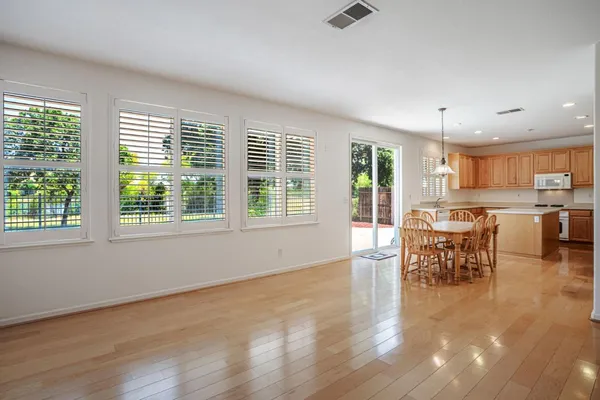 a kitchen with stainless steel appliances granite countertop a stove a refrigerator a sink dishwasher a dining table and chairs with wooden floor