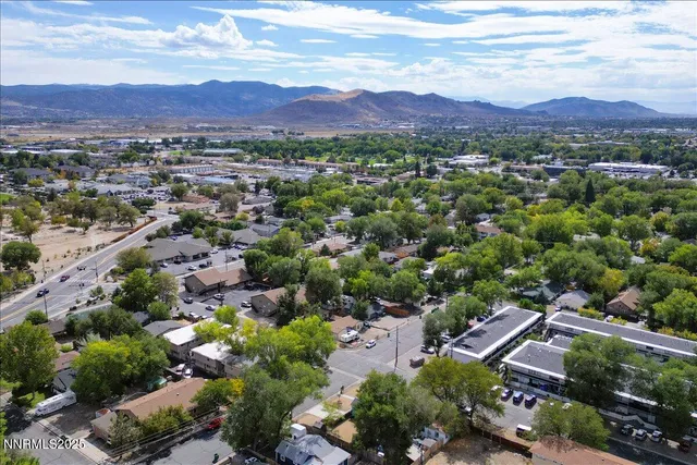 an aerial view of a city with lots of residential buildings and mountain view in back