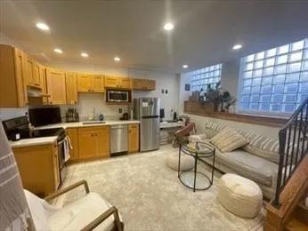 a living room with kitchen island furniture and a view of kitchen appliances