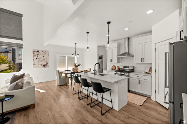 14728 South Canyon Pointe Road Draper, UT 84020 - Photo 11 of 35 Open-concept kitchen and living area featuring wood-finish flooring, white cabinetry, a kitchen island with seating, stainless steel appliances, and high vaulted ceilings