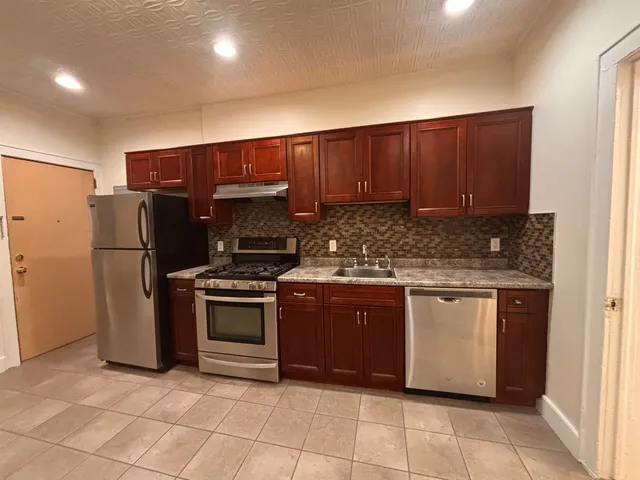 a kitchen with stainless steel appliances granite countertop a stove a refrigerator and a sink
