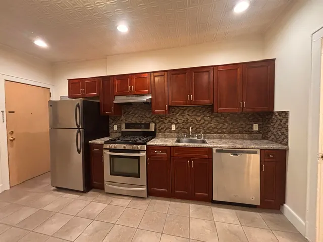 a kitchen with stainless steel appliances granite countertop a stove a refrigerator and a sink