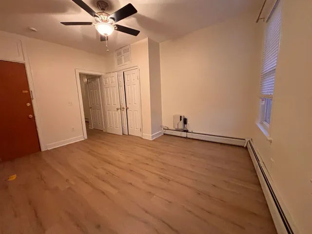an empty room with wooden floor fan and windows