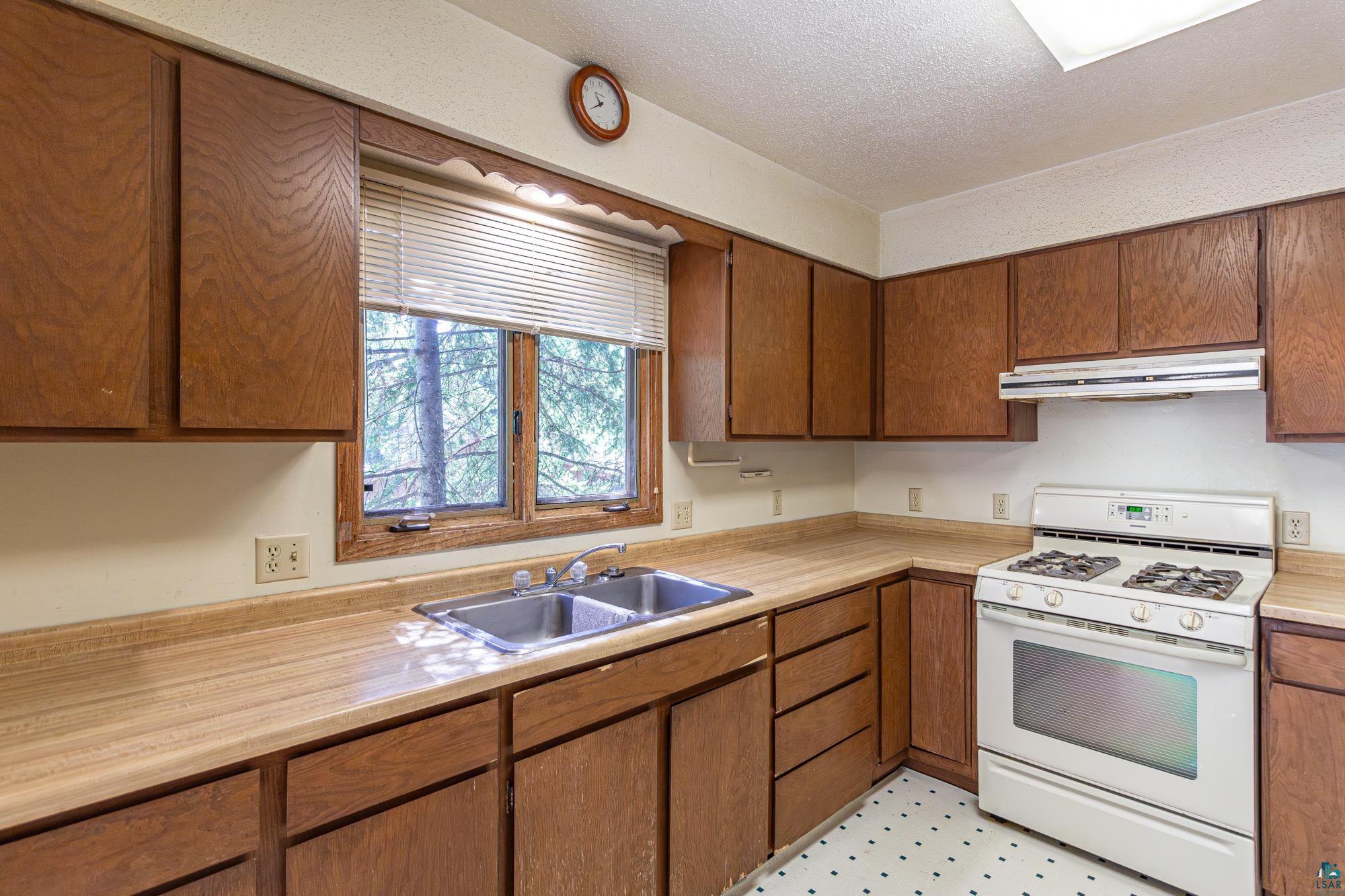 14687 North Country Road Ely, MN 55731 - Photo 3 of 44 Kitchen featuring a textured ceiling, sink, white gas range oven, and light tile floors