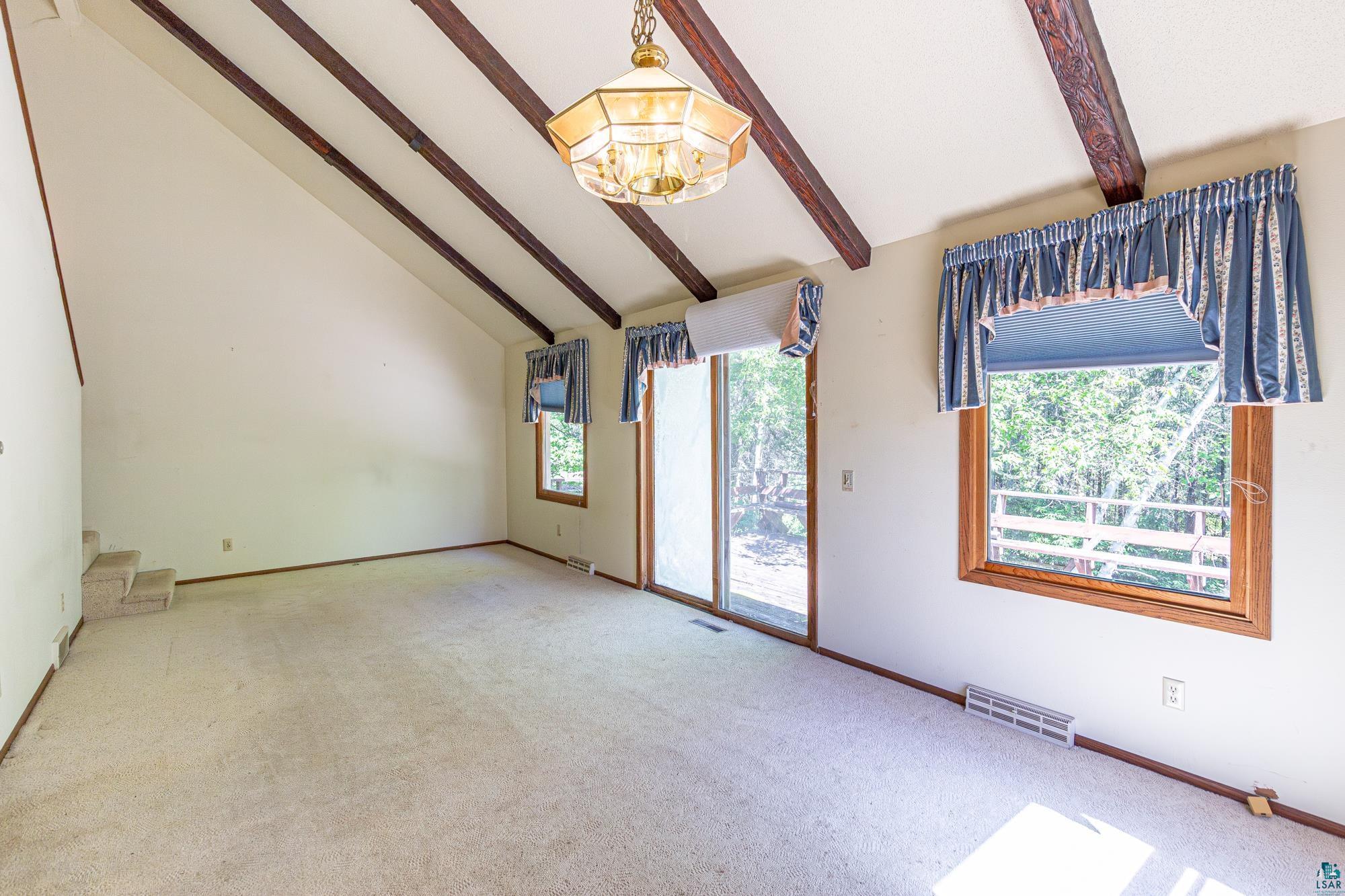 14687 North Country Road Ely, MN 55731 - Photo 7 of 44 Carpeted living room with a chandelier, plenty of natural light, and vaulted ceiling with beams