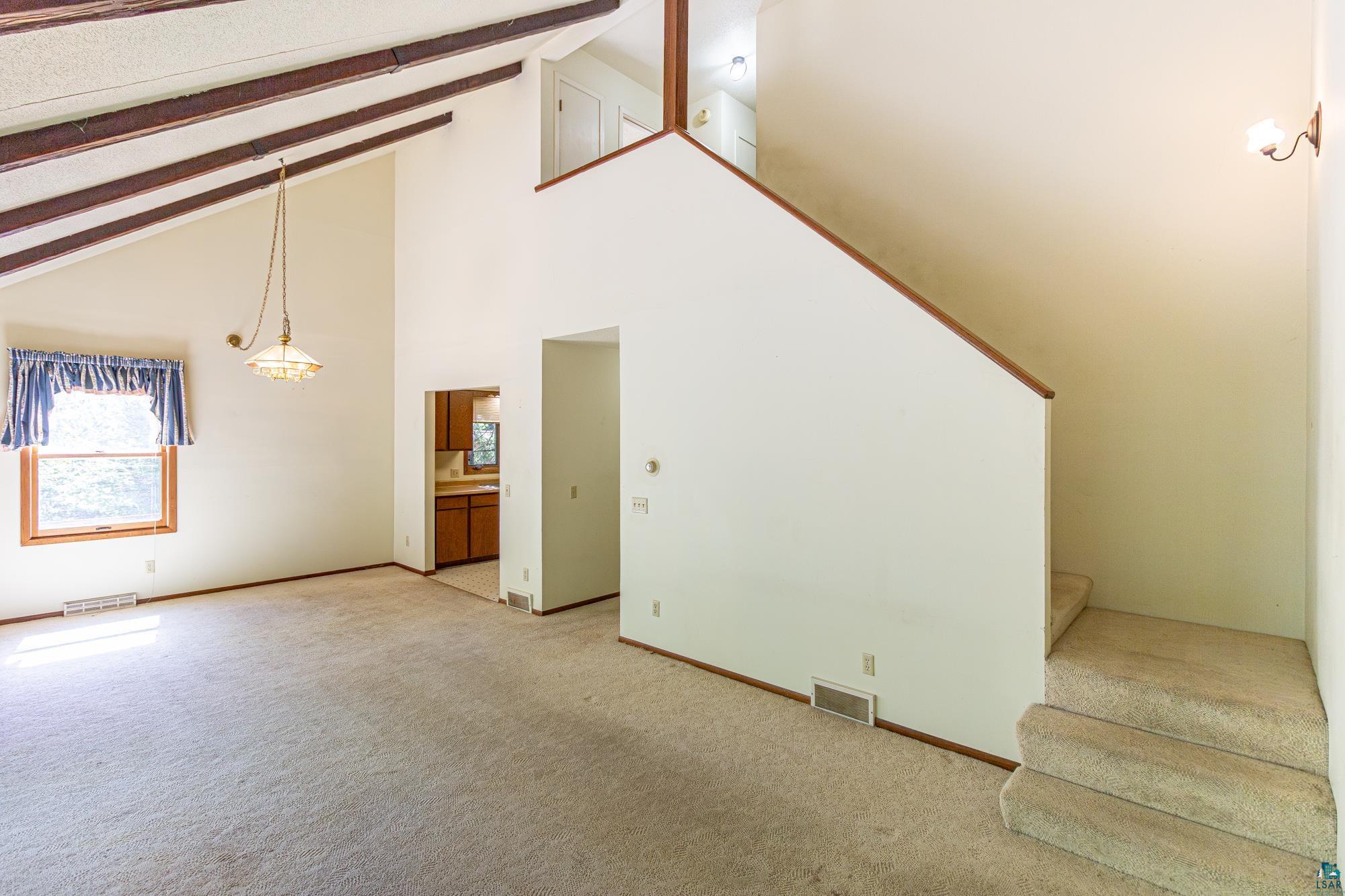 14687 North Country Road Ely, MN 55731 - Photo 8 of 44 Unfurnished living room featuring high vaulted ceiling, beam ceiling, and carpet floors