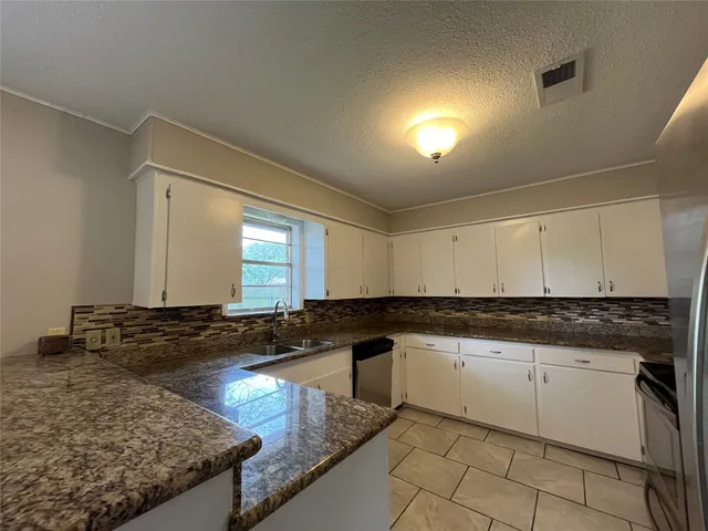 a kitchen with granite countertop a sink a stove and cabinets