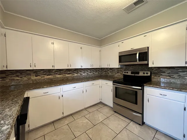 a kitchen with granite countertop white cabinets stainless steel appliances and a sink