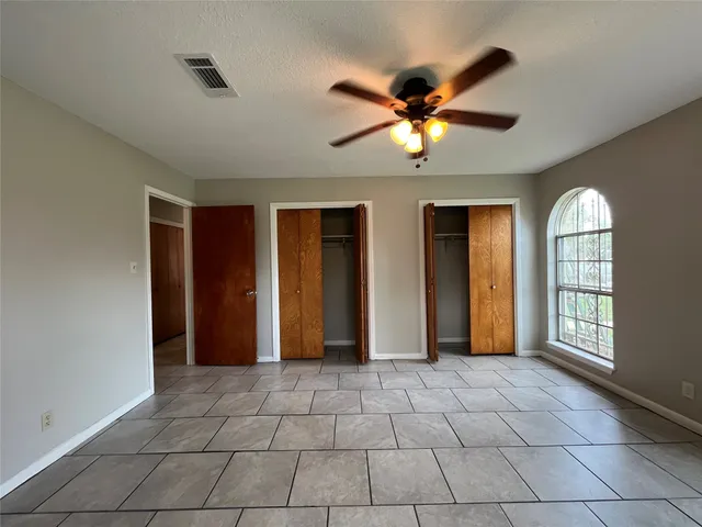 a view of an empty room with window and chandelier fan