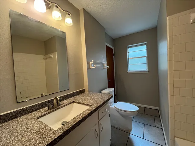 a bathroom with a granite countertop sink a toilet and a mirror