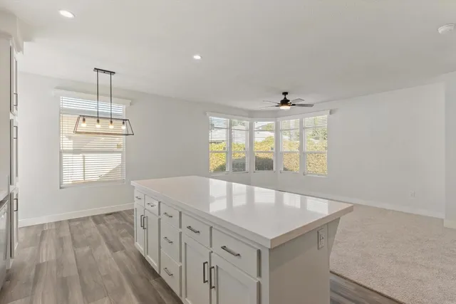 an empty room with windows and ceiling fan