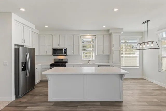 a kitchen with kitchen island stainless steel appliances a sink and refrigerator