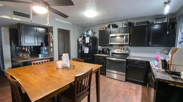 a kitchen with stainless steel appliances wooden floor dining table and chairs