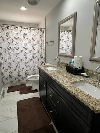 a bathroom with a granite countertop sink a toilet and mirror