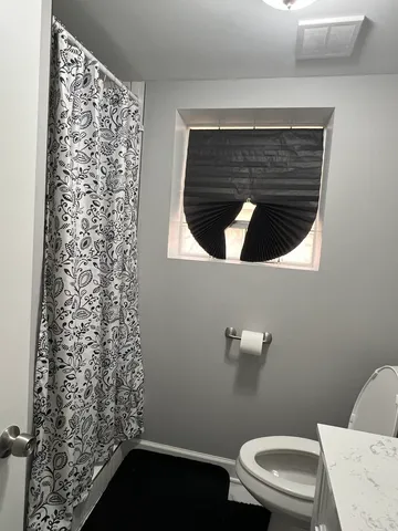a bathroom with a toilet and a shower curtain