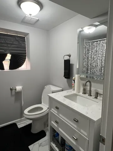 a bathroom with a granite countertop toilet sink and mirror
