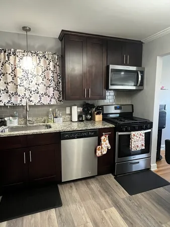 a kitchen with granite countertop a stove a sink and a microwave
