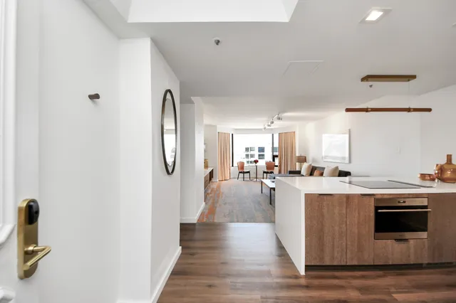 a living room with stainless steel appliances furniture a rug and a kitchen view