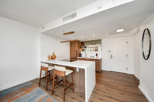 a kitchen with stainless steel appliances a dining table chairs and wooden floor