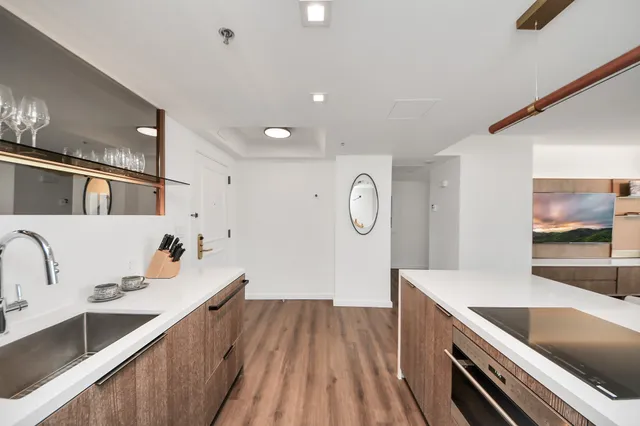 a large kitchen with a large counter top a sink a stove and wooden floor