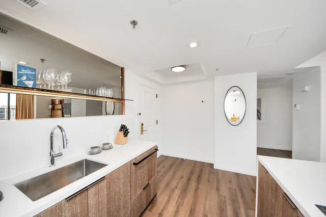 a living room with stainless steel appliances kitchen island granite countertop a sink a stove and wooden floors