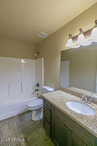 a bathroom with a granite countertop sink a toilet and a mirror
