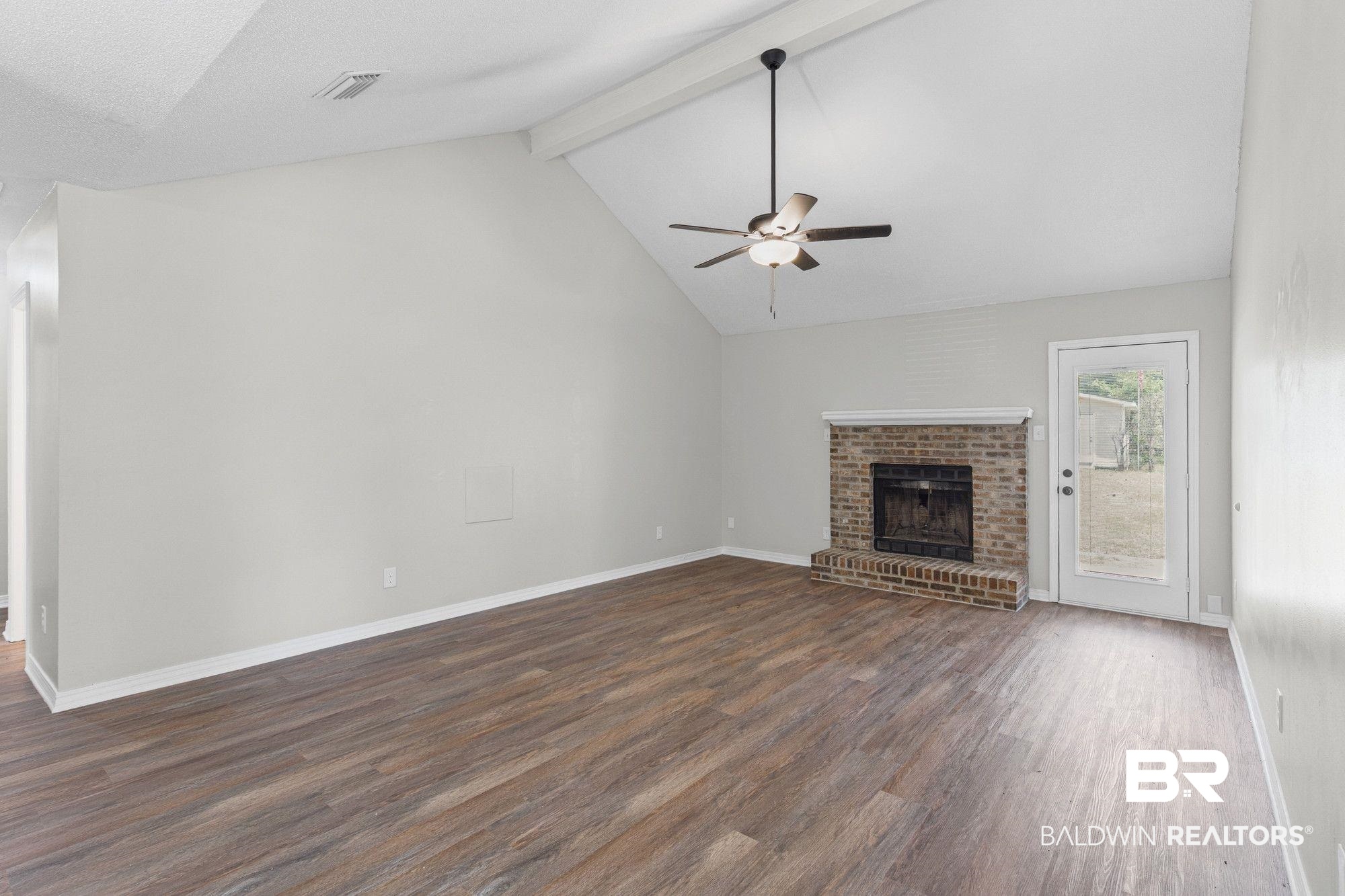 1301 Repoll Road Mobile, AL 36695 - Photo 3 of 21 Spacious room featuring vaulted ceilings, wood-finish flooring, and a brick fireplace with a white mantel