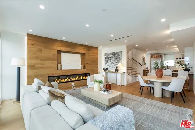 a living room with couches a coffee table and kitchen view with wooden floor