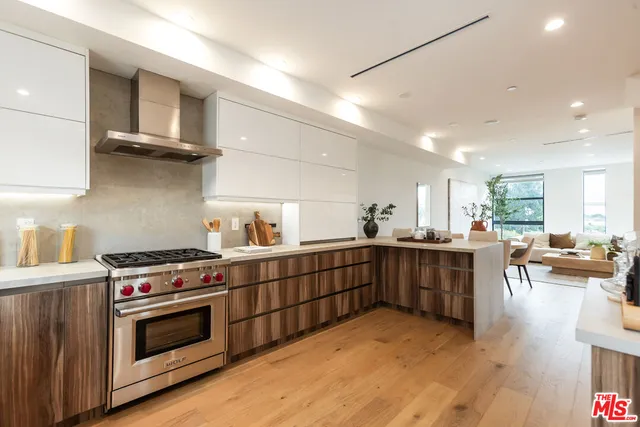 a kitchen with stainless steel appliances a stove a sink cabinets and wooden floor