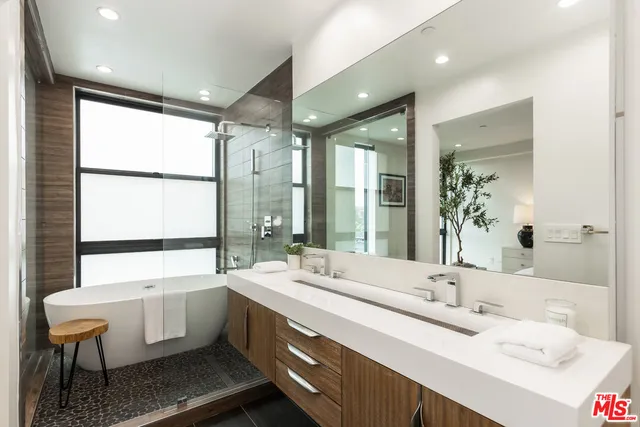 a bathroom with a double vanity sink large mirror and a bathtub
