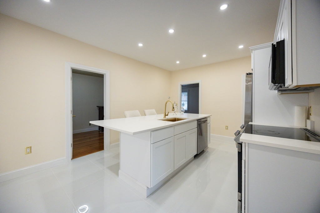 12 Lothrop Street Saugus, MA 01906 - Photo 6 of 42 a large white kitchen with a sink a refrigerator and a stove top oven