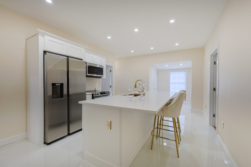 12 Lothrop Street Saugus, MA 01906 - Photo 8 of 42 a kitchen with stainless steel appliances granite countertop a refrigerator a sink a stove and a refrigerator with wooden floor