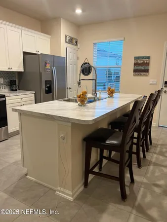 a kitchen with stainless steel appliances granite countertop a table chairs sink refrigerator and cabinets