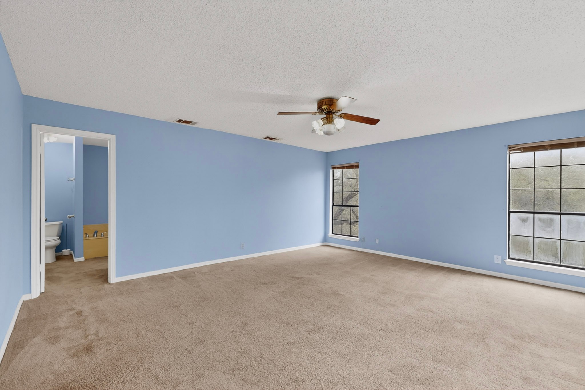 1003 Pier Branch Road Dripping Springs, TX 78620 - Photo 24 of 40 A spacious bedroom featuring neutral carpeting and a ceiling fan, offering a comfortable personal retreat.