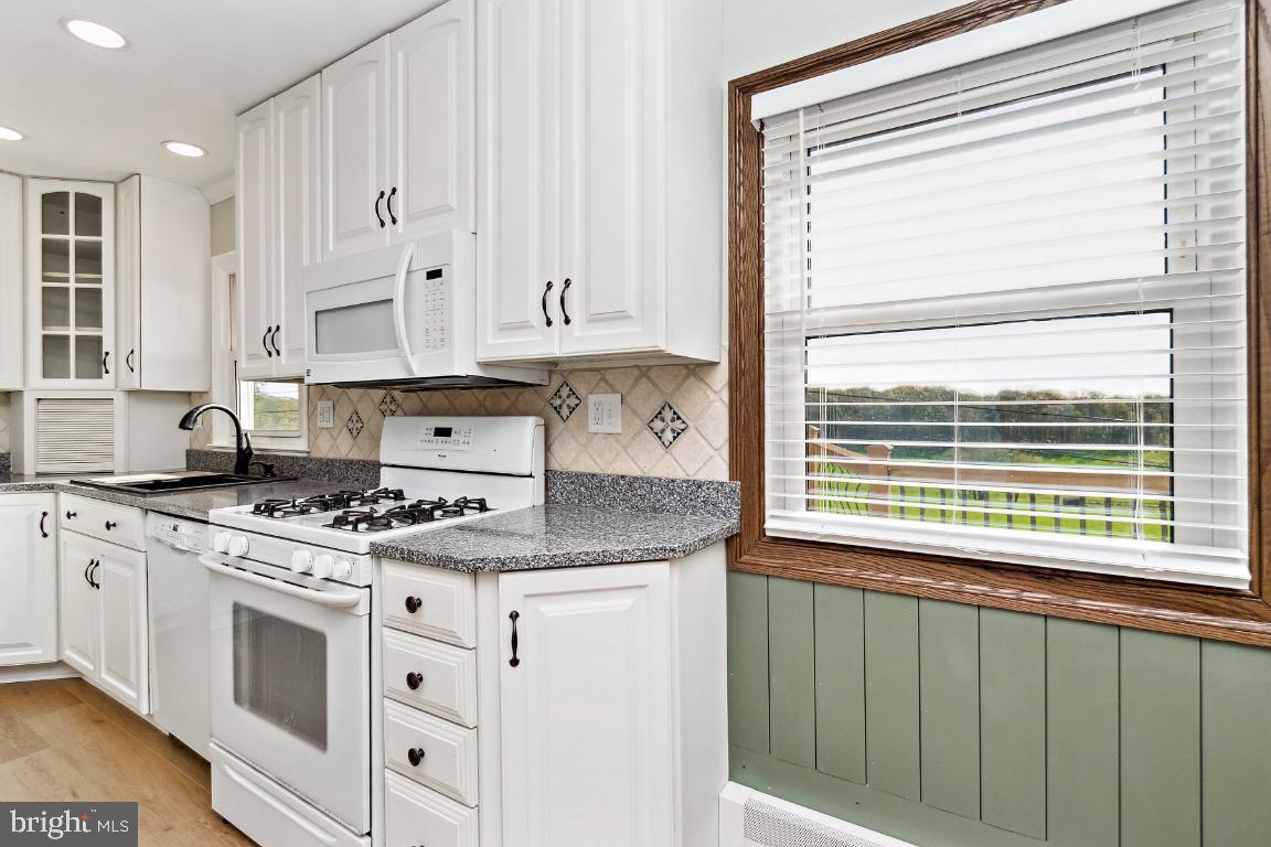 19422 Resh Mill Road Hampstead, MD 21074 - Photo 12 of 55 a kitchen with granite countertop a stove a sink and white cabinets