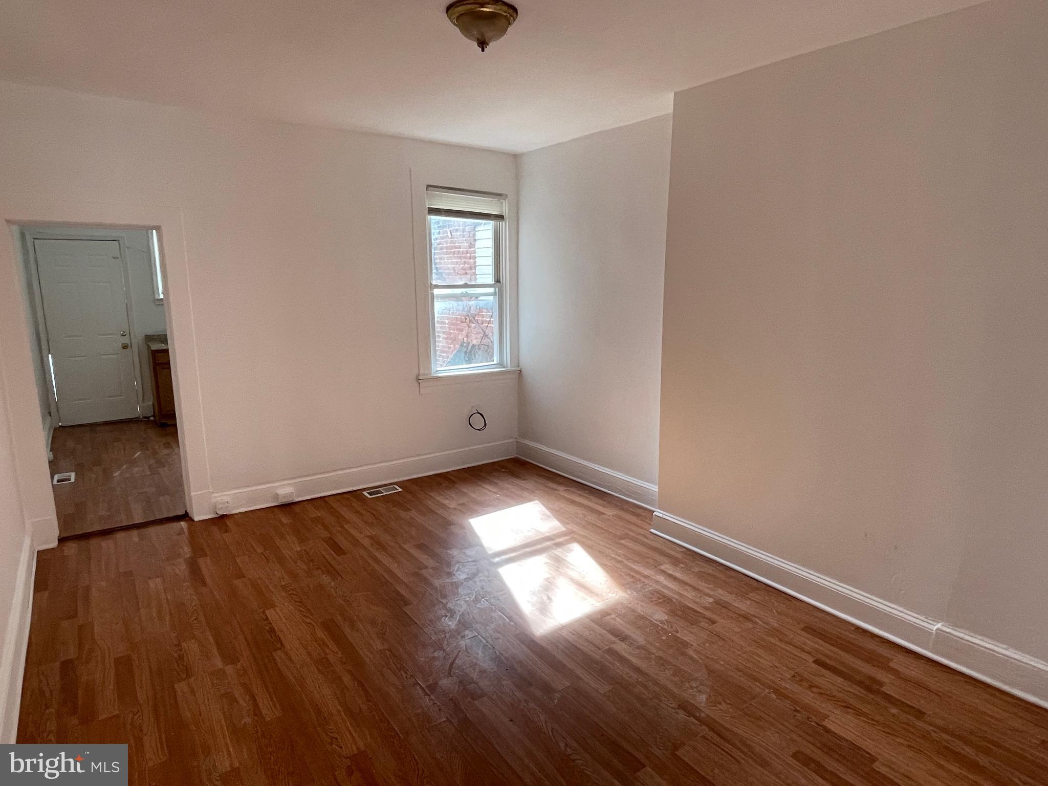 1314 Division Street Baltimore, MD 21217 - Photo 4 of 20 an empty room with wooden floor and windows