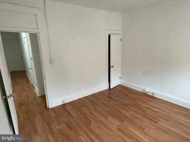 an empty room with wooden floor and mirror