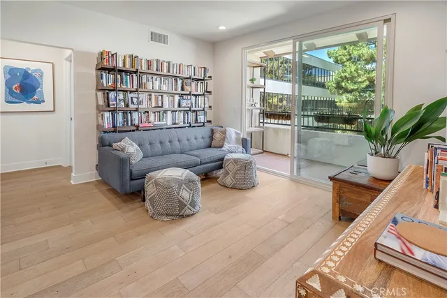 a living room with stainless steel appliances granite countertop furniture wooden floor and a window
