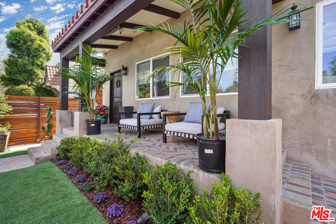 a view of a patio with table and chairs potted plants and large tree