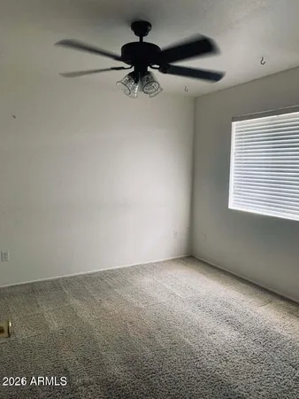 an empty room with a ceiling fan and window