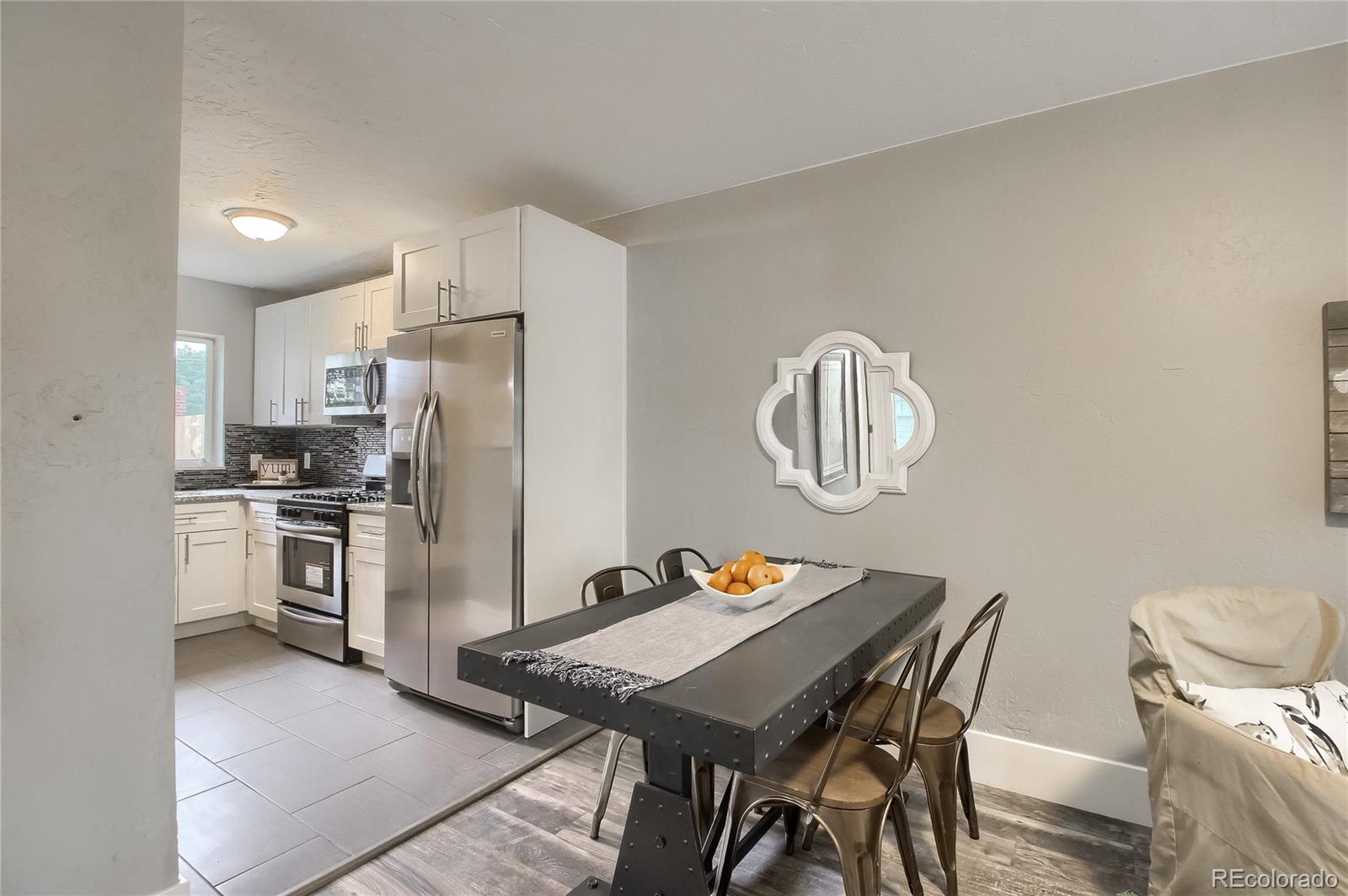 2821 Harrison Street Denver, CO 80205 - Photo 11 of 24 a kitchen with stainless steel appliances granite countertop a dining table chairs stove refrigerator and microwave