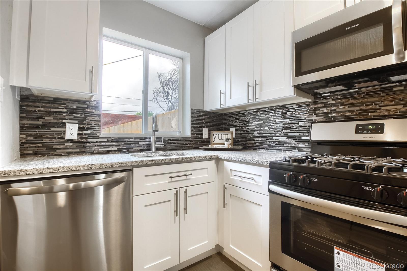 2821 Harrison Street Denver, CO 80205 - Photo 9 of 24 a kitchen with granite countertop a sink stainless steel appliances and white cabinets