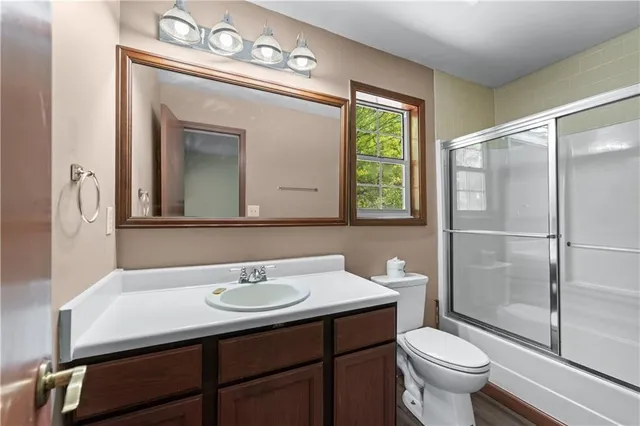 a bathroom with a sink a toilet a mirror and shower
