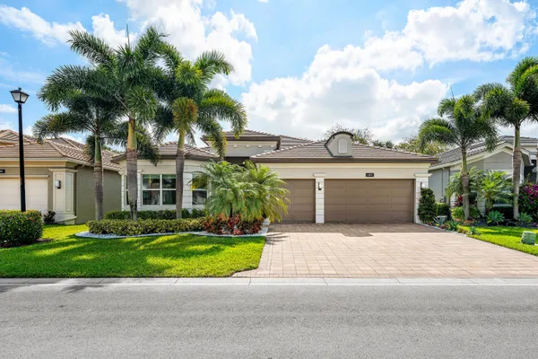 a view of a house with a yard and palm trees
