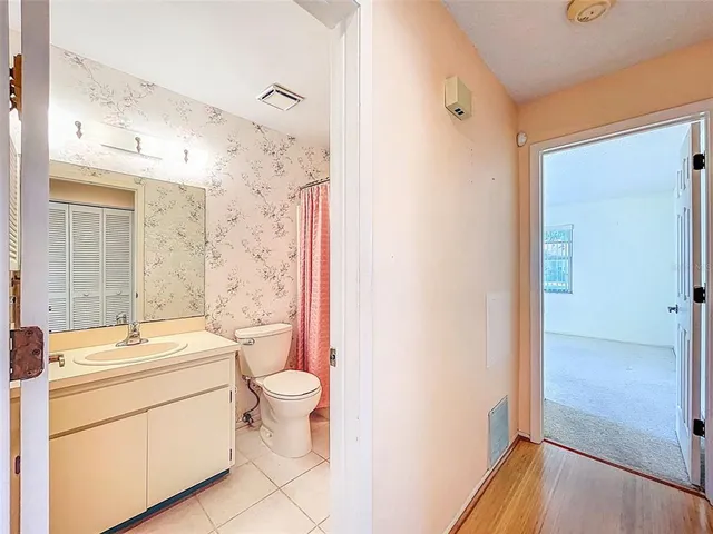 a bathroom with a granite countertop sink a toilet a mirror and shower